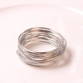 Close-up of a silver plated wire napkin ring with minimalist multilayered winding design - Silver