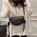 Vintage black saddle bag with cracked leather texture and woven geometric shoulder strap - Black