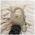 Detail showing white quilted leather texture and gold twist lock closure of the mini bag - White