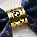 Hollow gold comma napkin ring with scroll pattern on a blue textured napkin - [Gold] Hollow Comma Napkin Ring
