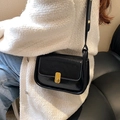 Bolso bandolera negro clásico con acabado brillante y cierre dorado usado por una modelo - Negro