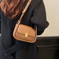 Bolso bandolera de cuero marrón vintage con cierre dorado sobre un abrigo de lana - Marrón