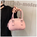 Pink bowling handbag with glossy finish and silver metal rings held by a model - Pink
