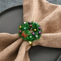 Kerst servetring met groene krans, kleurrijke bellen en rode strik op een stoffen servet - Groen