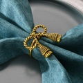 Elegant gold bow napkin ring with twisted rope design and tassels on blue linen napkin - Antique Gold