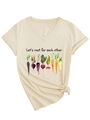Detail of V-neck apricot tee featuring vegetable print and stylish side knot design - Sand (Black Graphic)