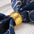 Elegante gouden metalen servetring met geometrische textuur op donkerblauw servet - Goud