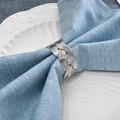 Silver woven metal napkin ring on blue linen napkin and white porcelain plate - Silver