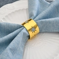 Golden snowflake metal napkin ring on blue linen napkin and white porcelain plate - Gold
