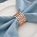 Rose gold hollow wave napkin ring on a light blue linen napkin and white ceramic plate - 1 Piece / Rose Gold