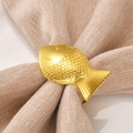 Elegant gold fish-shaped metal napkin ring featuring detailed scales on light linen - Gold