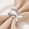 Silver fish shaped napkin ring with scale texture on light cotton napkin and white plate - Silver
