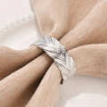 Polished silver woven metal napkin ring with braided texture on a beige linen napkin - Silver