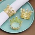 Gouden kroon servetringen met parels en strass op een groen bord achtergrond - Goud