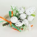 Detail of wooden Easter napkin ring with speckled eggs, green leaves, and ribbons - White