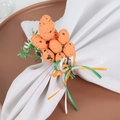 Detail of Easter napkin ring with orange speckled eggs, green leaves, and colorful ribbons - Orange