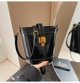 Primer plano de un bolso de mano negro de cuero brillante con un cierre dorado - Negro