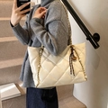 Beige Stepp-Tote Bag mit goldener Kette und Schleifenanhänger auf schlichtem Hintergrund - Mit Anhänger / Gebrochenes Weiß