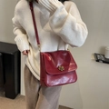 Vintage dark red leather crossbody bag with golden floral buckle on white sweater - Burgundy