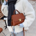 Caramel brown matte faux leather handbag with gold buckle in an autumn street setting - Caramel color