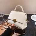 Elegante bolso bandolera cuadrado blanco crema con cierre dorado sobre mármol - Blanco Roto