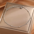 Classic silver bead chain anklet with lobster clasp on elegant golden silk fabric background - Silver
