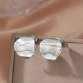 Polished silver irregular wavy round stud earrings in stainless steel on a jewelry box - Silver Irregular Wave Surface Style (F502)