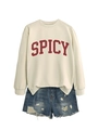 Close-up of cream crewneck sweatshirt featuring red Spicy print and distressed denim shorts - Sand
