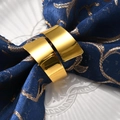 Macro detail of polished gold napkin rings on blue embroidered fabric and white plate - Gold Polished Blade Napkin Ring / Gold