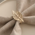 Rond de serviette en forme de feuille dorée avec texture veinée sur lin beige - Doré