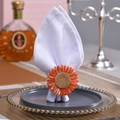 Detail eines handgefertigten Sonnenblumen-Serviettenrings aus orangefarbenen Fasern - Künstliche Orange Blume