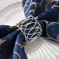 Macro shot of silver metal napkin ring with hollow geometric circles on blue fabric - Woven X-shaped Hollow Style / Silver