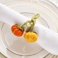 Detail of handmade knit pumpkin napkin rings in orange and yellow on a white plate - Pumpkin Bow Style / Orange and Yellow