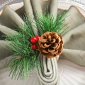 Christmas napkin ring with pine cones, red berries and green needles on a white plate - Christmas Pine Cone Napkin Ring