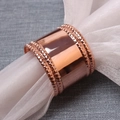 Rond de serviette perlé en or rose poli avec gaze blanche sur une table texturée grise - Or rose