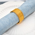 Elegant gold metal mesh napkin ring on blue fabric placed on a white ceramic plate - Gold