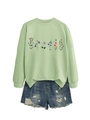 Close-up of light green sweatshirt with colorful floral print and distressed denim shorts - Olive Green
