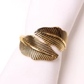 Macro shot of vintage gold leaf napkin ring with intricate feather texture and plating - Antique Gold