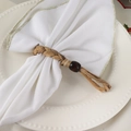 Portatovagliolo intrecciato a mano con perla in legno e nappe su piatto bianco elegante - Portatovagliolo Intrecciato in Paglia Fatto a Mano Con Perla in Legno