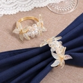 Golden woven napkin ring set with crystal leaves on a navy blue napkin for table setting - Crystal Woven Flower / Gold
