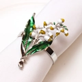 Detalle de un servilletero de esmalte con flores blancas y amarillas sobre tela blanca - Estilo Lirio de los Valles de Esmalte Plateado