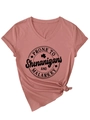 Détail d'un t-shirt à col en V rose poudré avec motif Prone to Shenanigans - Or Rose (Police Noire)