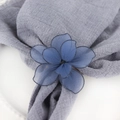 Détail du rond de serviette fleur en résille bleue sur un tissu de lin gris - Bleu