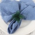 Gros plan d'un rond de serviette fleur 3D vert sur serviette bleue et assiette blanche - Vert
