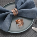 Rose gold leaf napkin rings in spiral design on a blue napkin and dark green plate - Rose Gold
