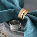 Leaf-shaped rose gold and silver metal napkin rings displayed on a premium dinner table set - Silver