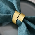 Elegante vergulde metalen servetring met piramidestructuur op blauwe linnen servetten - Piramide Textuur Stijl / Goud