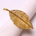 Golden vintage leaf napkin ring featuring intricate brushed texture on a white fabric - Gold