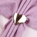 Vue macro d'un rond de serviette en forme de cœur doré brillant sur une serviette violette - Rond de Serviette en Forme de Coeur / Doré