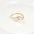 Detailed view of elegant gold napkin ring featuring a large white pearl on a ceramic plate - Pearl Napkin Ring / Gold